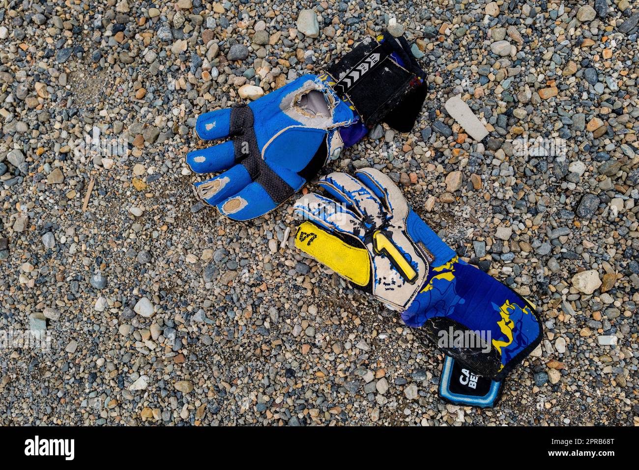 A pair of worn out goalkeeper’s gloves is seen lying on a dirt playing field during a football match in Quibdó, Chocó, Colombia. Stock Photo