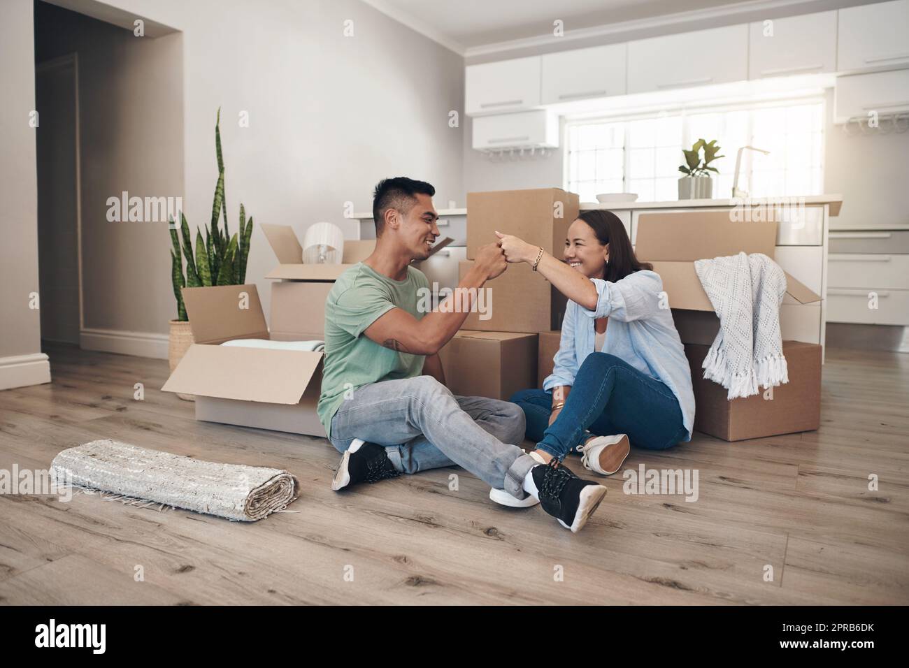 This is the first of many other things well achieve together. a couple sharing a fist bump while moving into their new home. Stock Photo