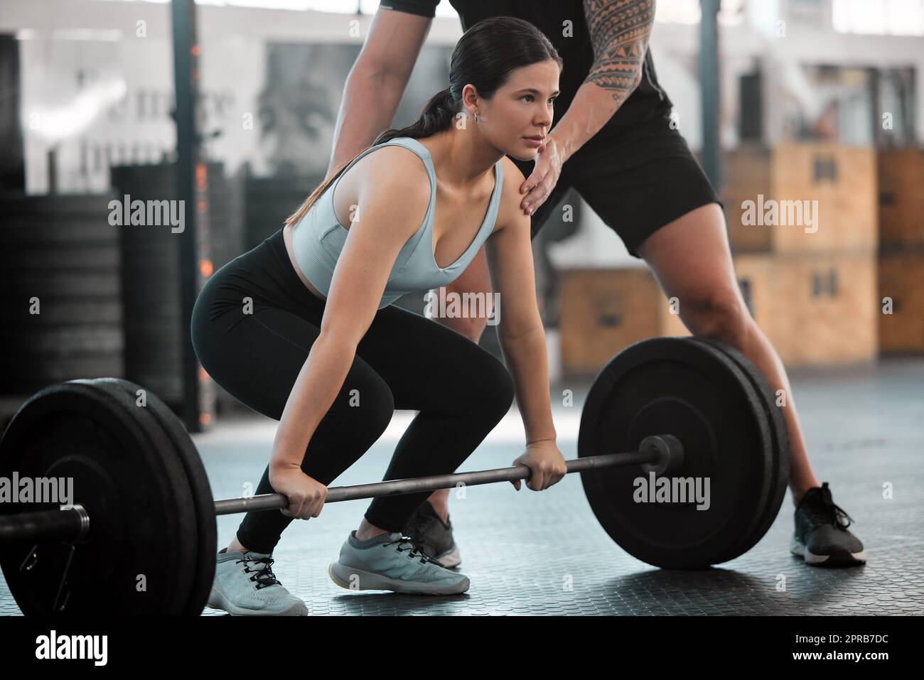 Tough young woman exercising with barbell. Determined female athlete  lifting heavy weights Stock Photo - Alamy