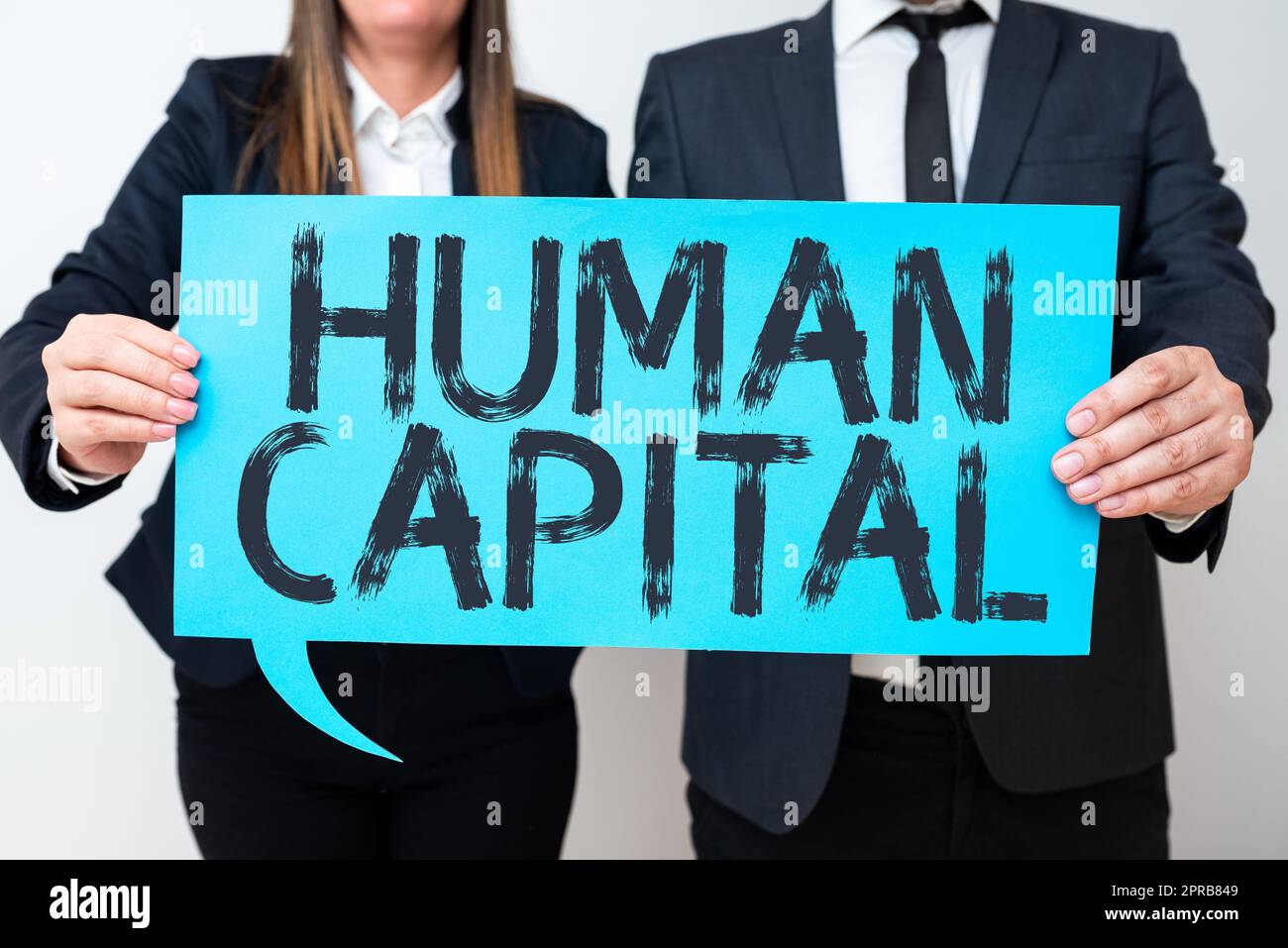 Text sign showing Human Capital. Internet Concept Intangible Collective Resources Competence Capital Education Business Team Holding Important Information On Speech Bubble On Both Sides. Stock Photo