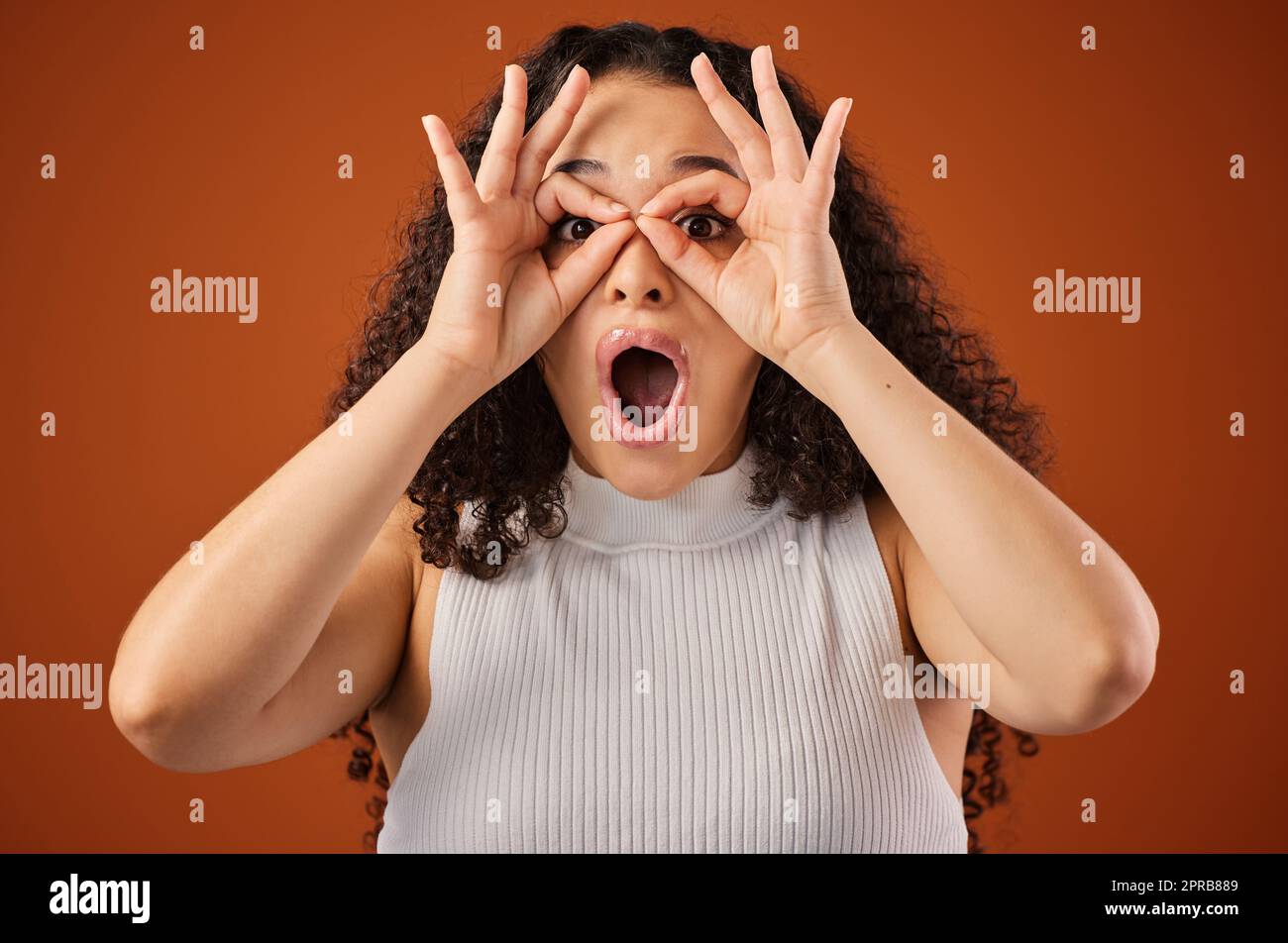 Oh wow Everythings so clear. Cropped portrait of an attractive young woman making a face in studio against a red background. Stock Photo