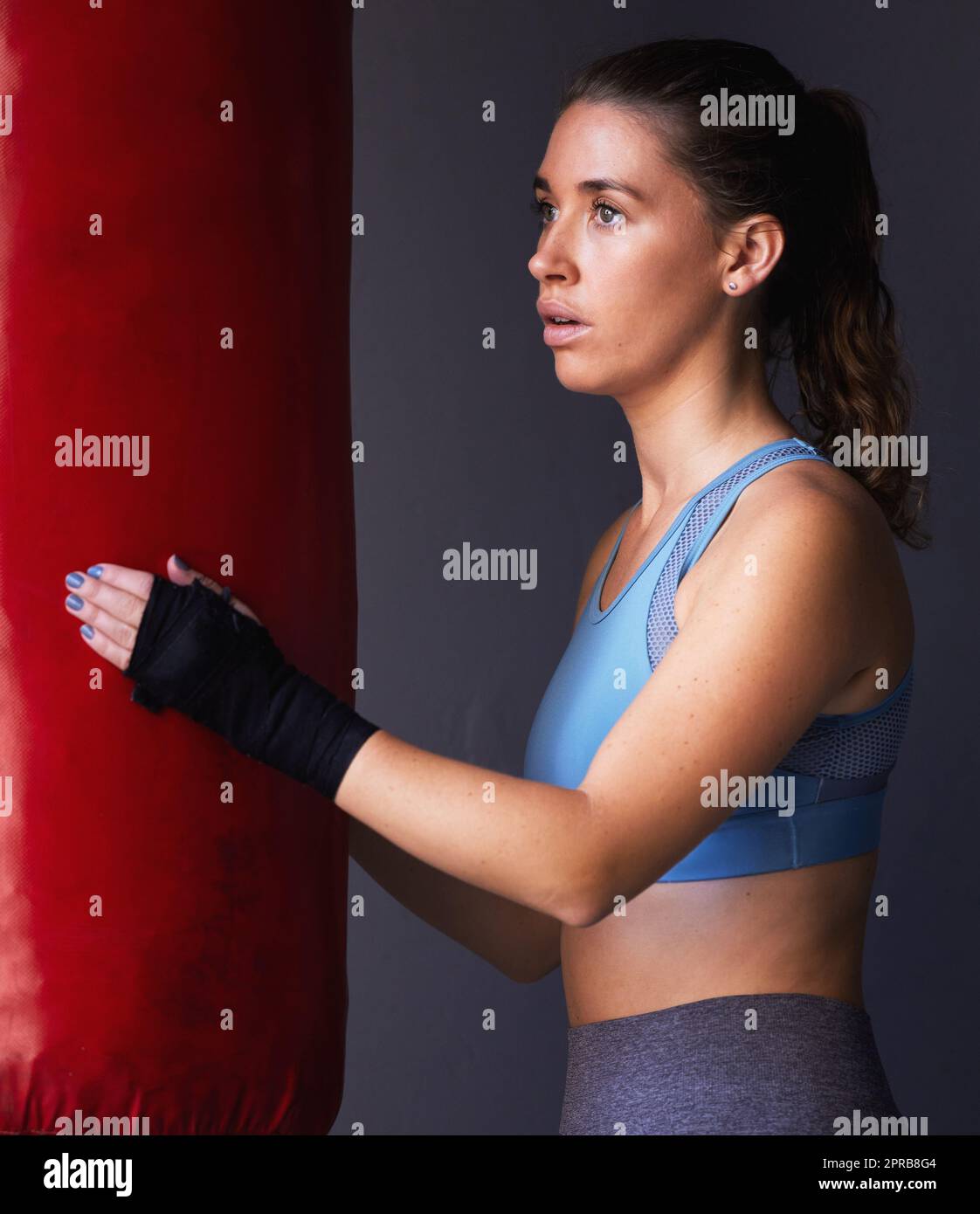 Stay strong and complete the challenge. a sporty young woman boxing against a grey background. Stock Photo