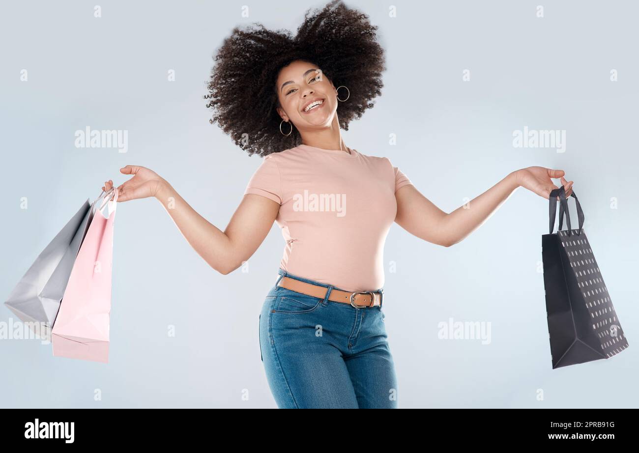 Bargains make me jump for joy. Studio portrait of a young woman jumping while carrying a bunch of shopping bag. Stock Photo