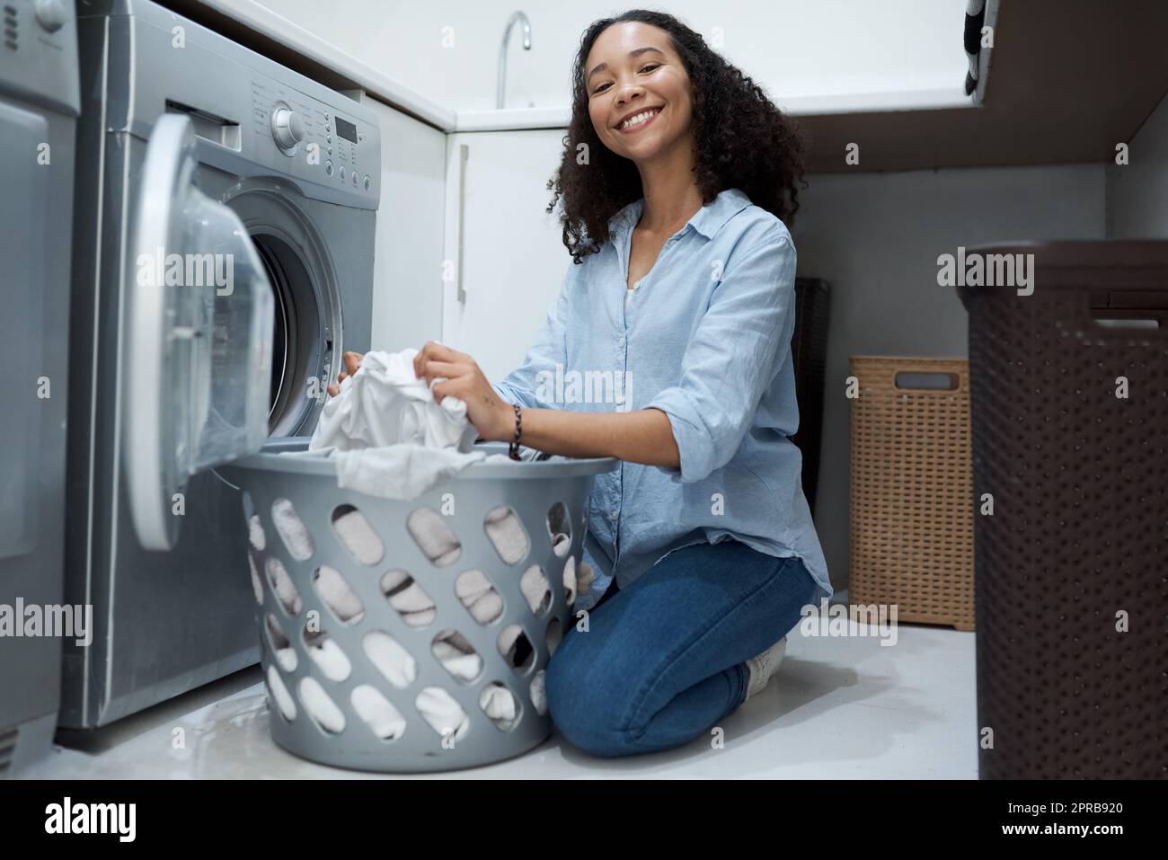 Nothing like a fresh clean load of washing. a young woman preparing to wash a load of laundry at home. Stock Photo