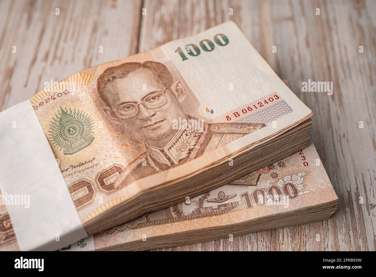 Stack of Thai baht banknotes on wooden background, business saving finance investment concept. Stock Photo