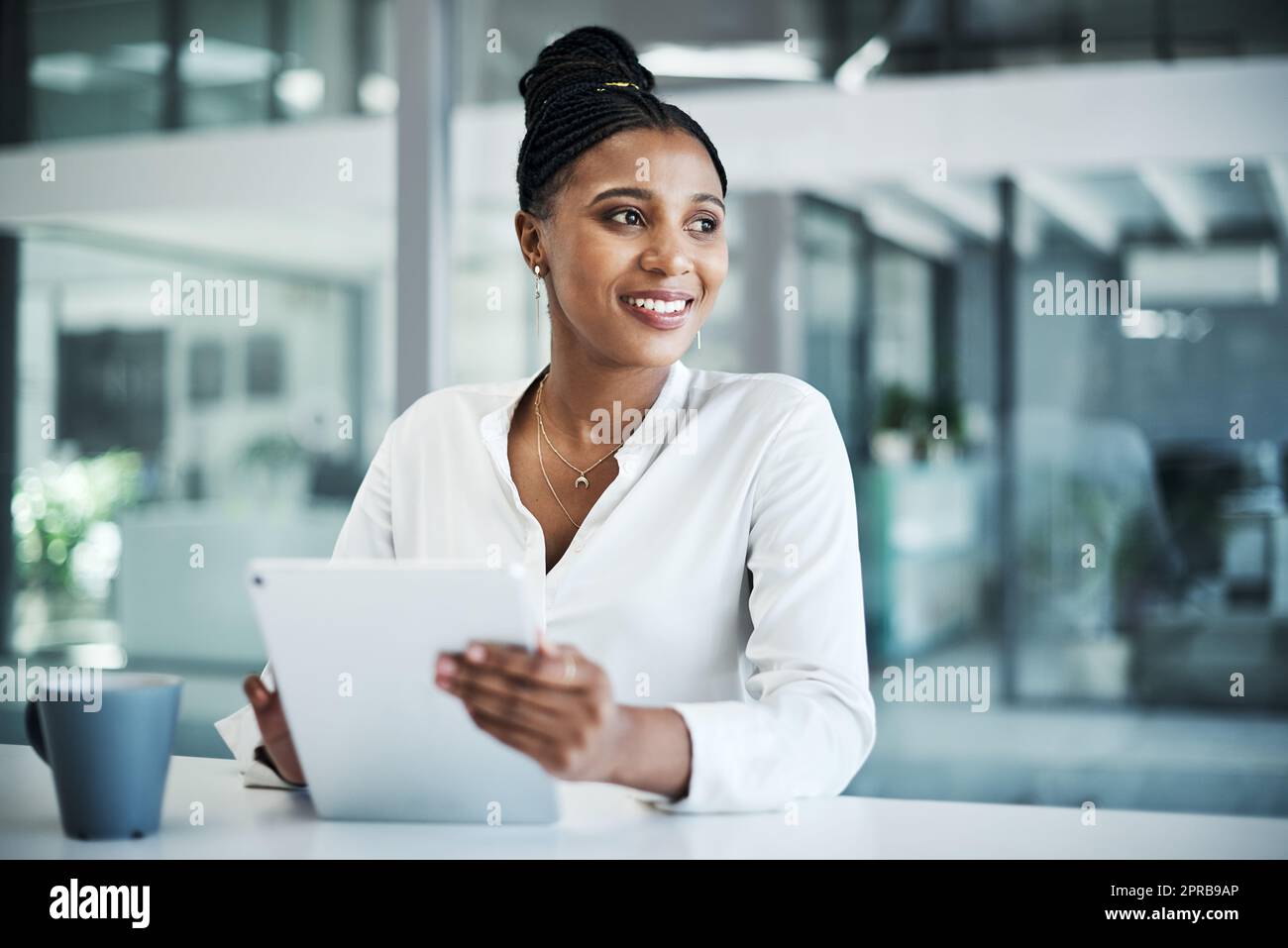 Believe it is yours and youre halfway there. an attractive young businesswoman sitting alone in her office and using a digital tablet. Stock Photo