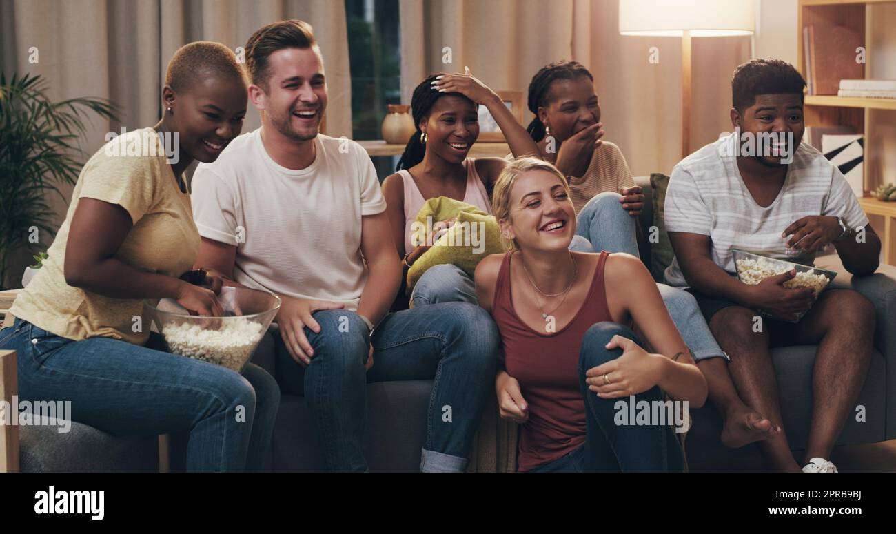 That scene was ridiculously funny. a group of a diverse group of friends relaxing in the lounge at home. Stock Photo