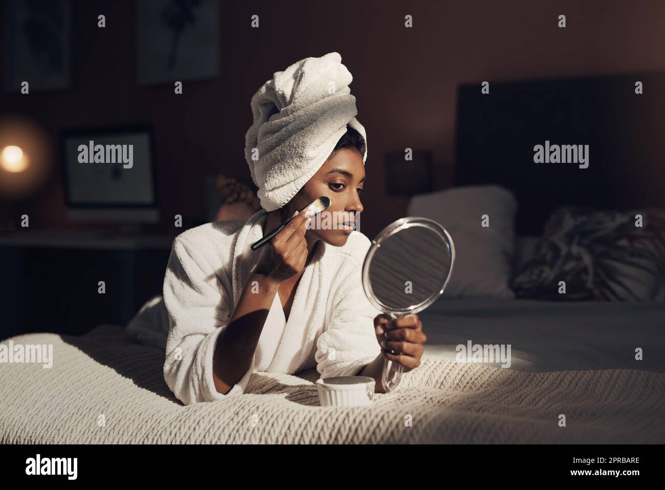 Pamper time is the closest experience to heaven on earth. a young woman giving herself a facial at home. Stock Photo