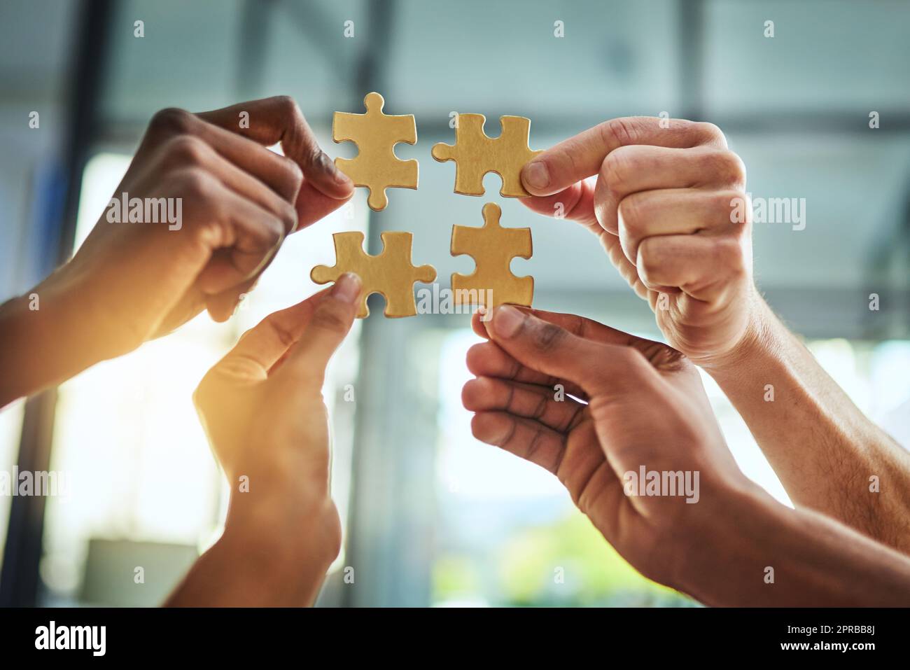 Group of business people holding puzzle pieces. Professionals connect and collaborate together inside office building. Closeup of hands, and team working together on a new strategy for success Stock Photo