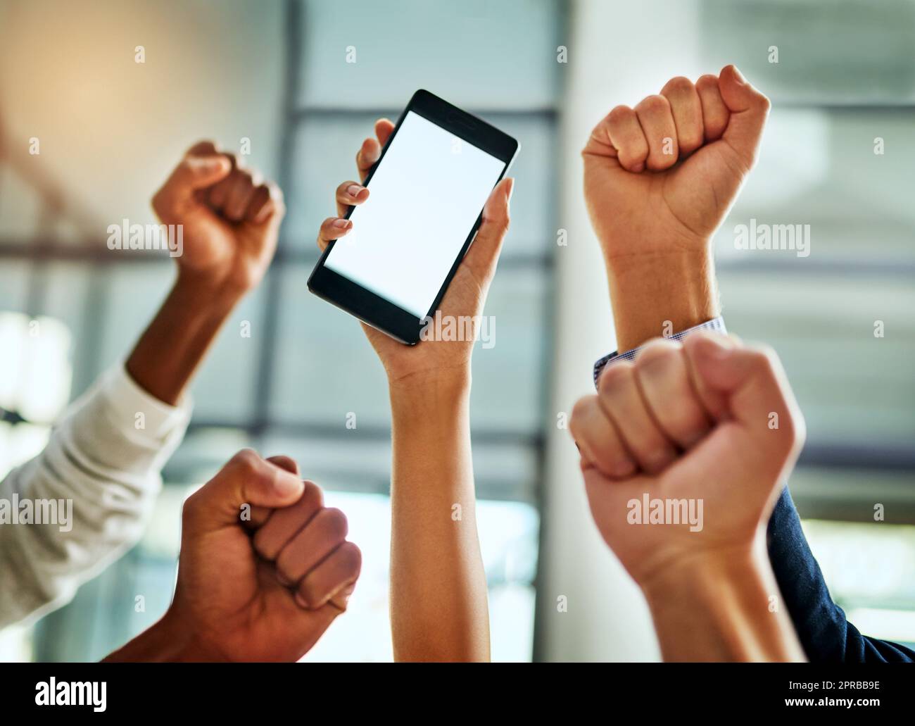 Hands of business people cheering and celebrating good news on a phone with blank screen for copy space inside. Excited team of office workers showing hand gesture for success, victory and winning Stock Photo