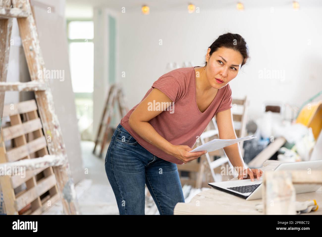 Woman construction manager checking project documentation, using laptop Stock Photo