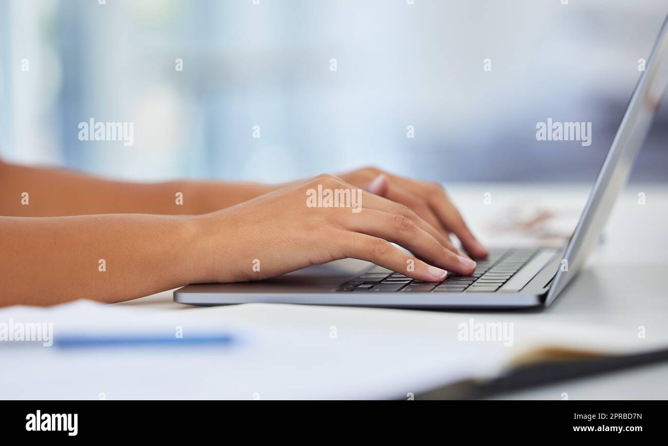 This new laptop has been a joy to use. an anonymous sitting at their desk typing on their laptop. Stock Photo