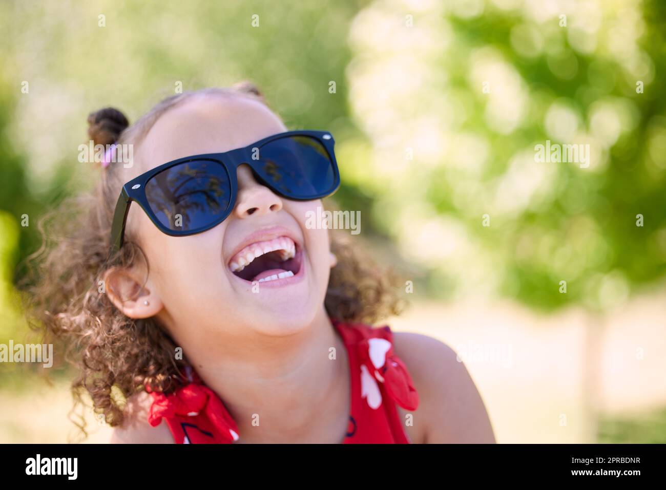 Youll find me having fun on the sunny side. an adorable little girl wearing sunglasses while at the park. Stock Photo