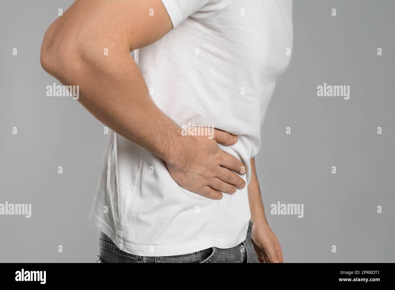 Man suffering from pain in lower right abdomen on light grey background