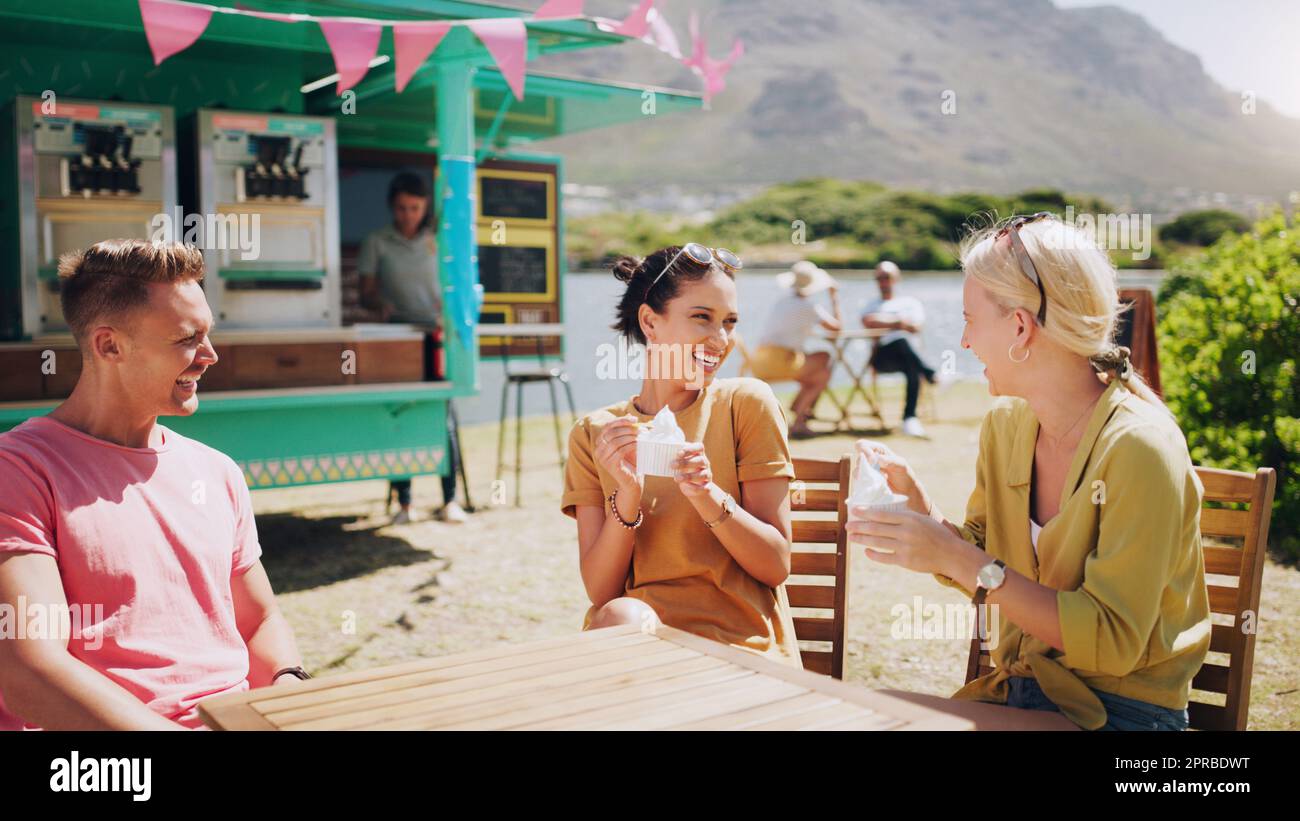 Gossiping over some ice cream. a group of friends eating ice cream and hanging out outside. Stock Photo