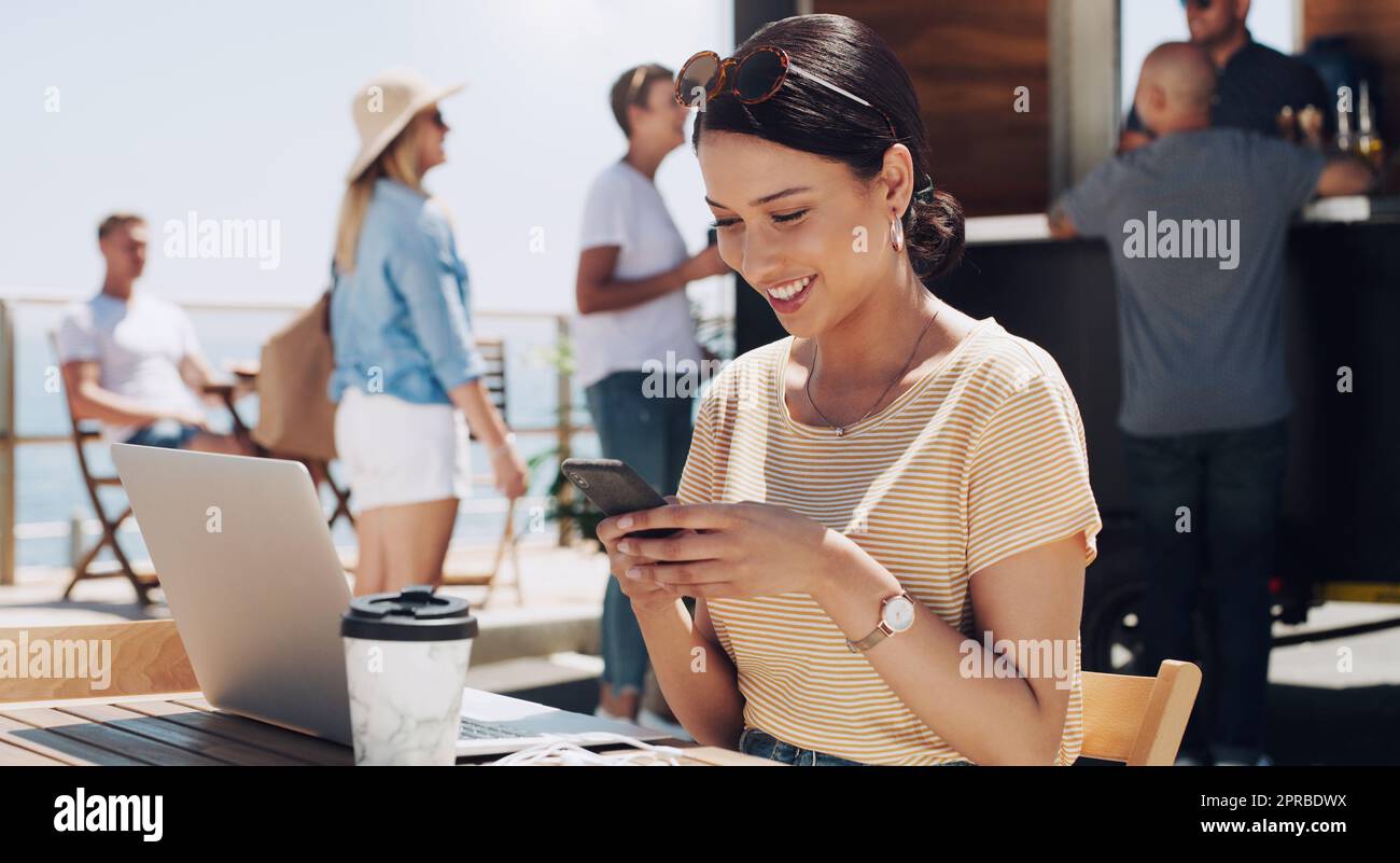 The sunshine and your texts are all I need. a young woman using her phone and working while sitting outside. Stock Photo