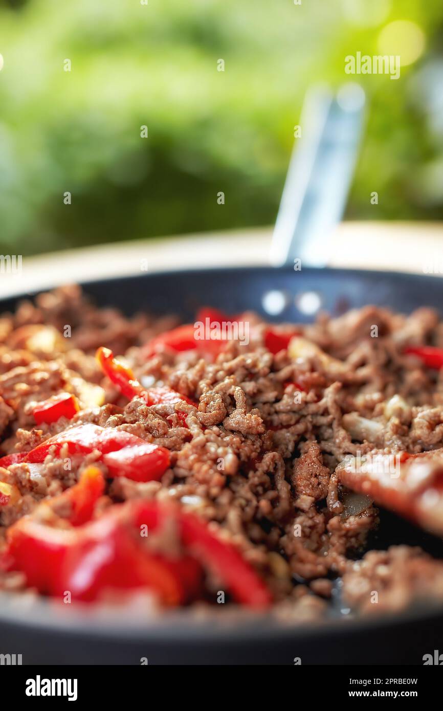 Food stuff. Still life Close up view of hot juicy ground beef stewed with tomato sauce, spices, basil, finely chopped vegetables in a frying pan, classic recipe. Stock Photo