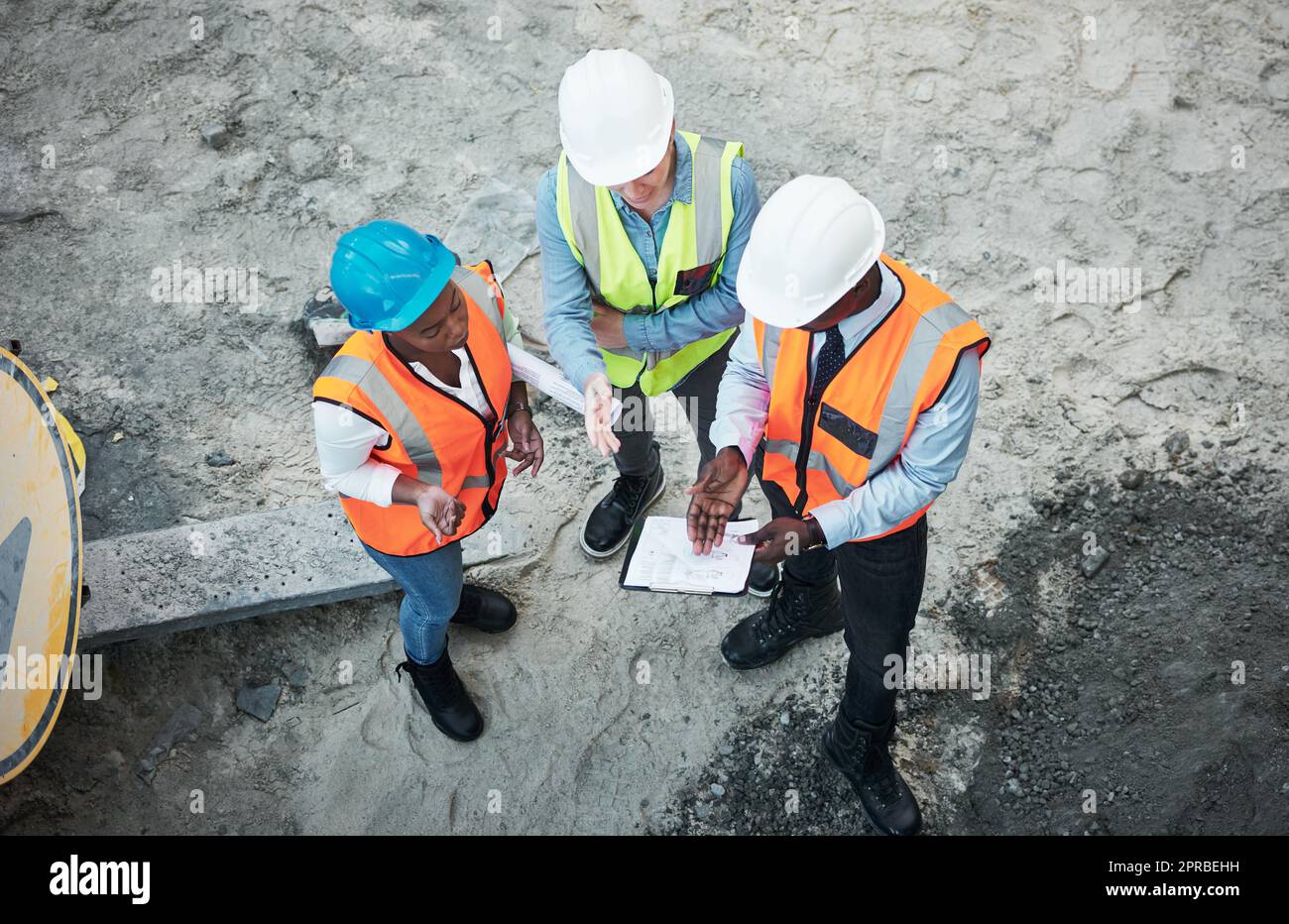 The hardest work happens out in the field. a group of builders going over building plans at a construction site. Stock Photo