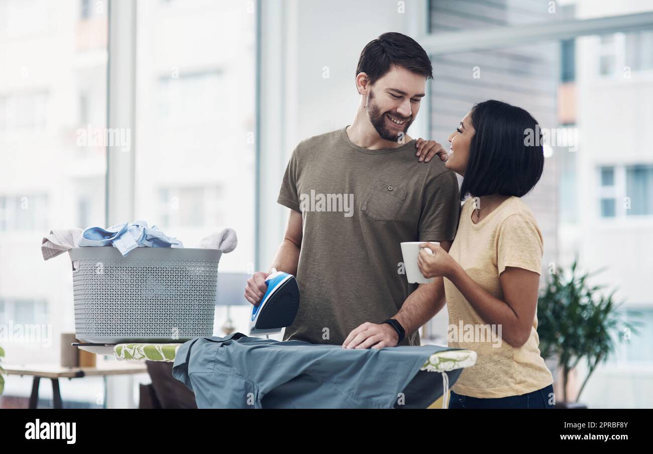 It takes two to make a marriage work. a happy young couple ironing freshly washed laundry together at home. Stock Photo
