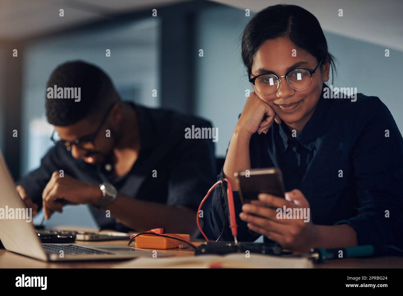 Computer not responding No worries, she will. a young technician using a smartphone while repairing computer hardware. Stock Photo