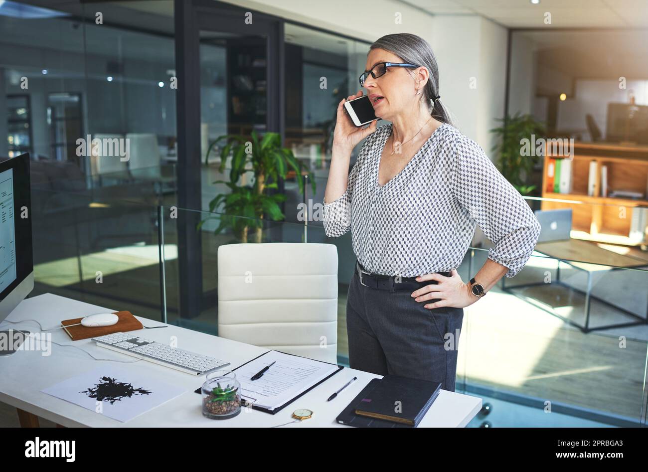 Cant talk in person She does phone consultations too. a confident mature psychologist using a smartphone in a modern office. Stock Photo