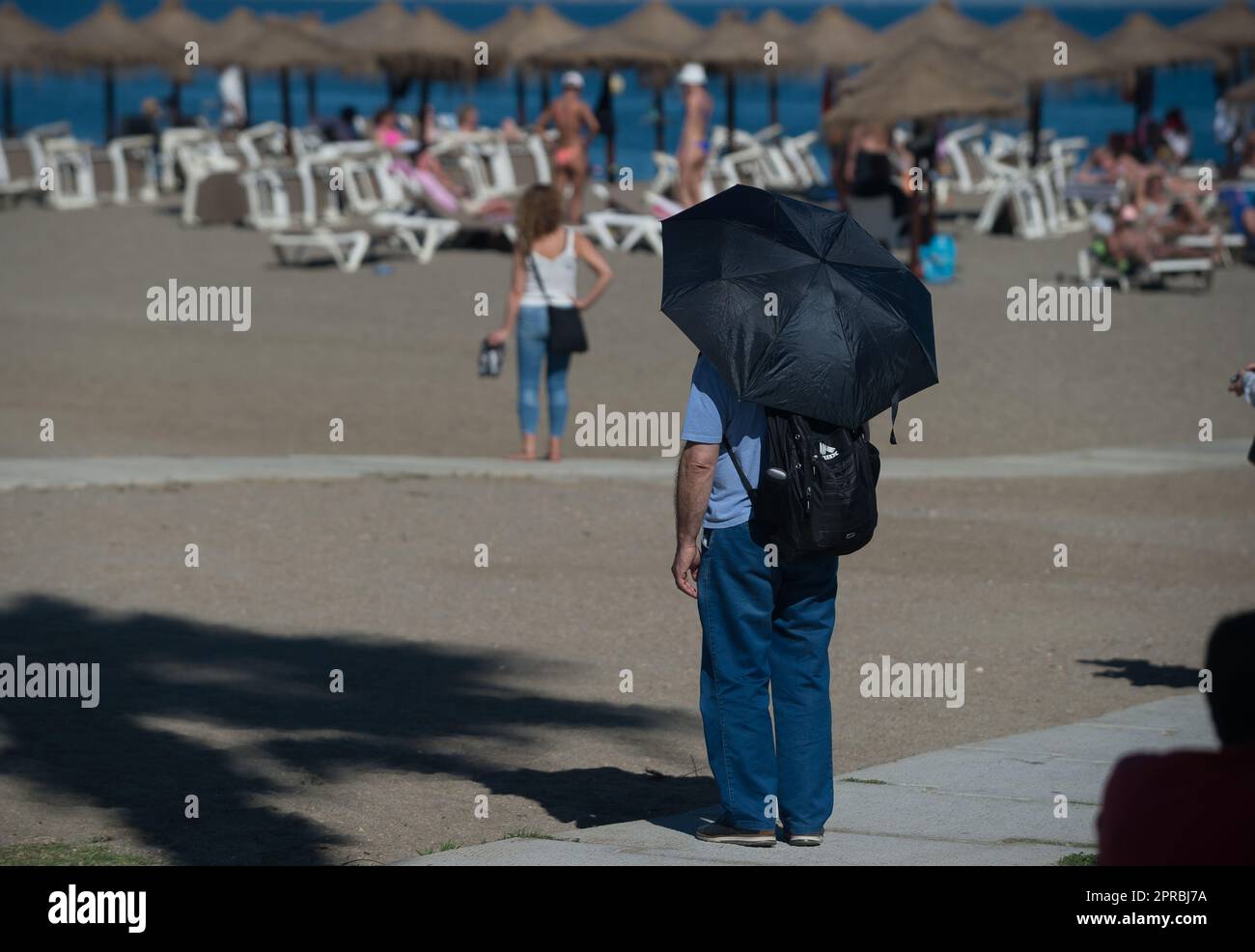 Malaga, Spain. 26th Apr, 2023. A man, who is using an umbrella to protect himself from the sun, is seen at 'La Malagueta beach' during an unusual heat wave. Spain is experiencing an unusual episode of high temperatures in April, months before the beginning of summer. According to the Spanish State Meteorological Agency, temperatures of over 35 degrees will be reached in most of the country. (Credit Image: © Jesus Merida/SOPA Images via ZUMA Press Wire) EDITORIAL USAGE ONLY! Not for Commercial USAGE! Stock Photo