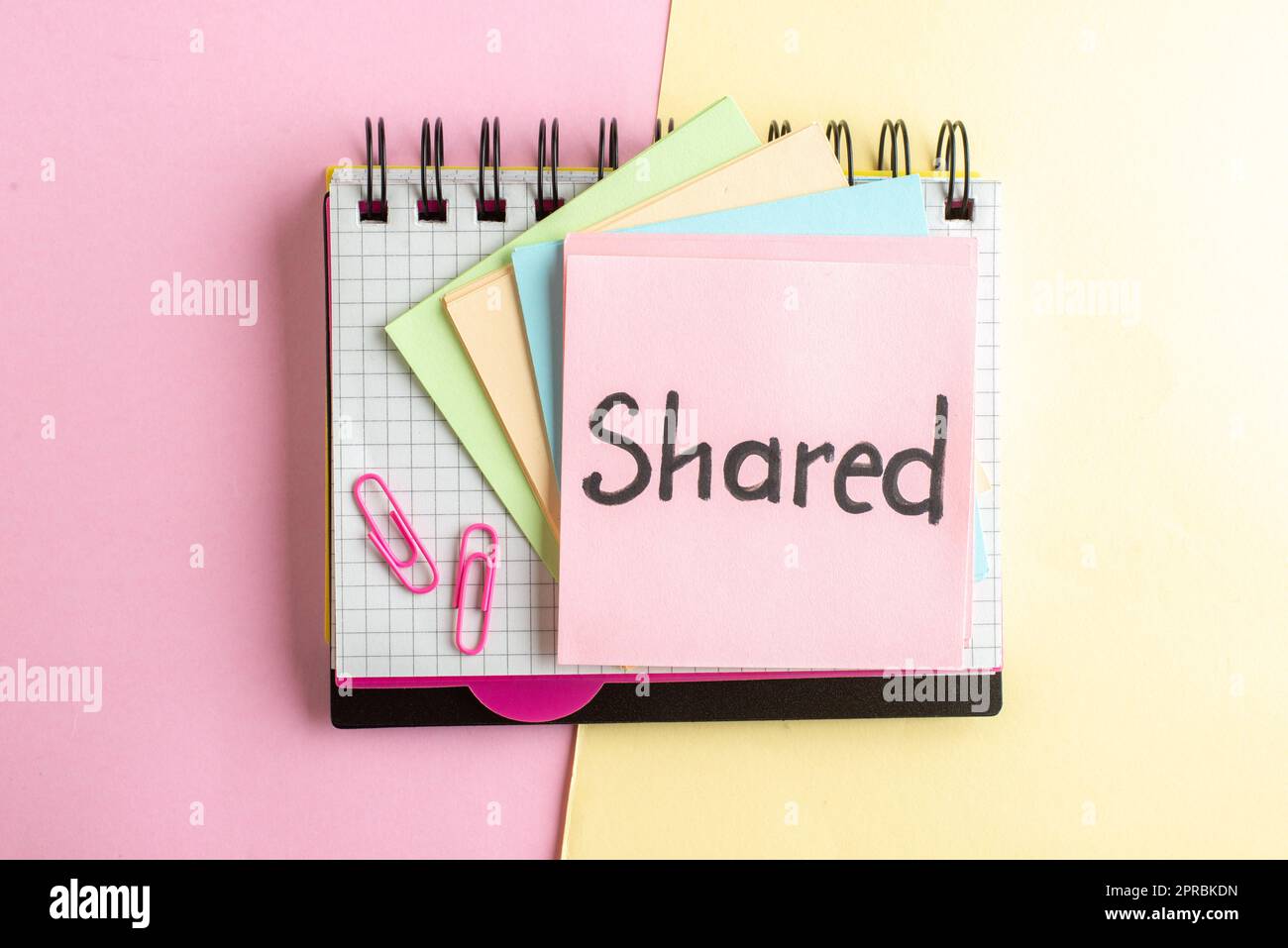 top view shared written note with stickers on yellow-pink background ...