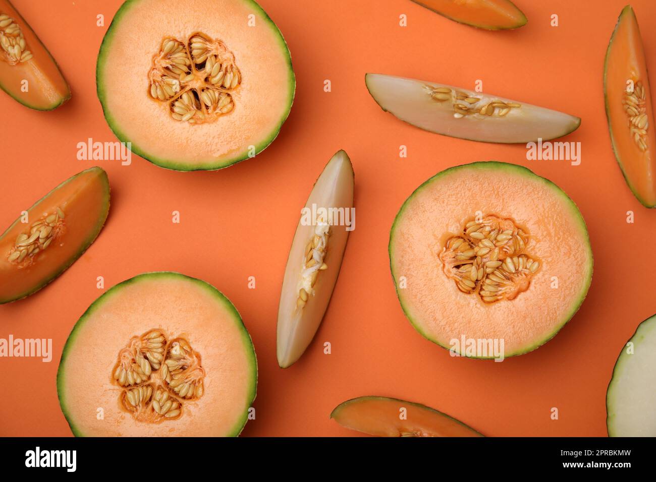 Cut different types of melons on orange background, flat lay Stock