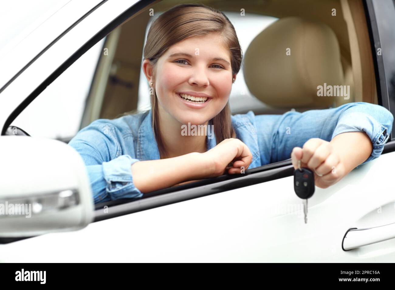 Her first car. A pretty young teenager smiling while sitting in her