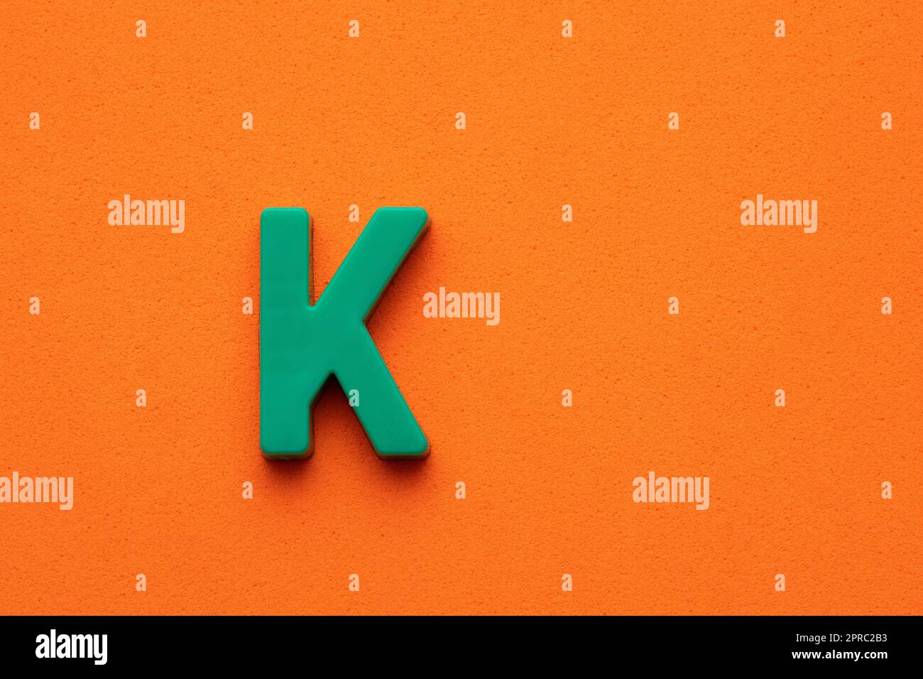Letter K green plastic uppercase on orange foamy background Stock Photo ...