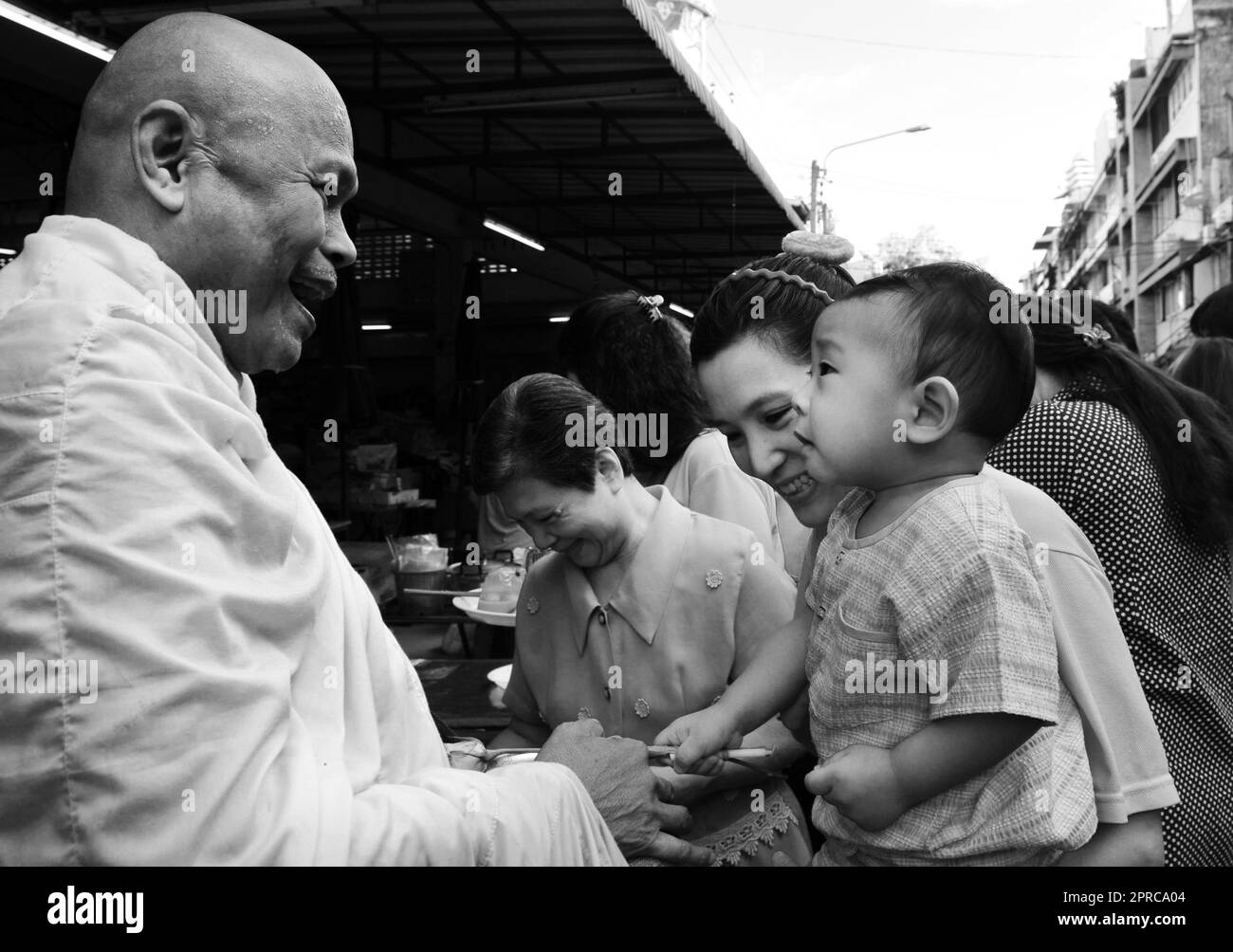 A Thai Buddhist monk blessing locals and receiving alms as part of a morning ritual. Photo taken in Bangkok, Thailand. Stock Photo