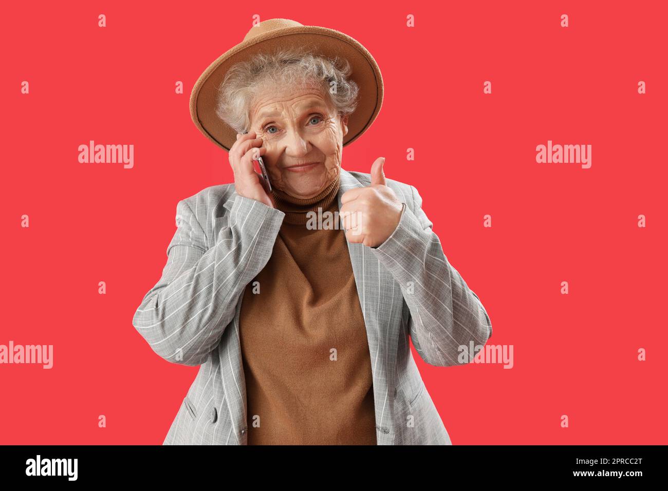 Senior woman talking by mobile phone on red background Stock Photo - Alamy