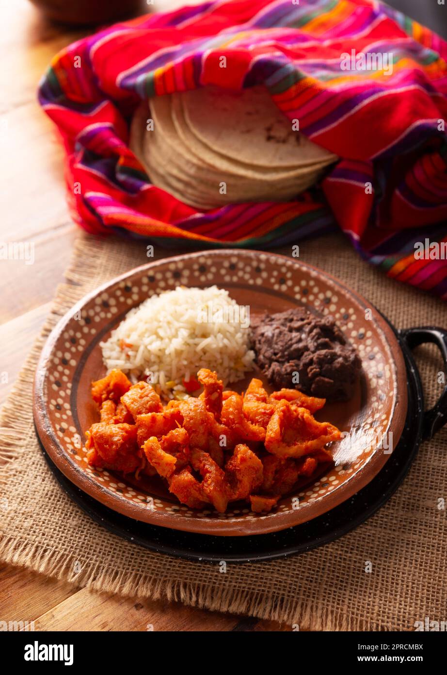 Pork rinds stewed in red sauce accompanied by rice and refried beans. Traditional homemade dish very popular in Mexico, this dish is part of the popul Stock Photo