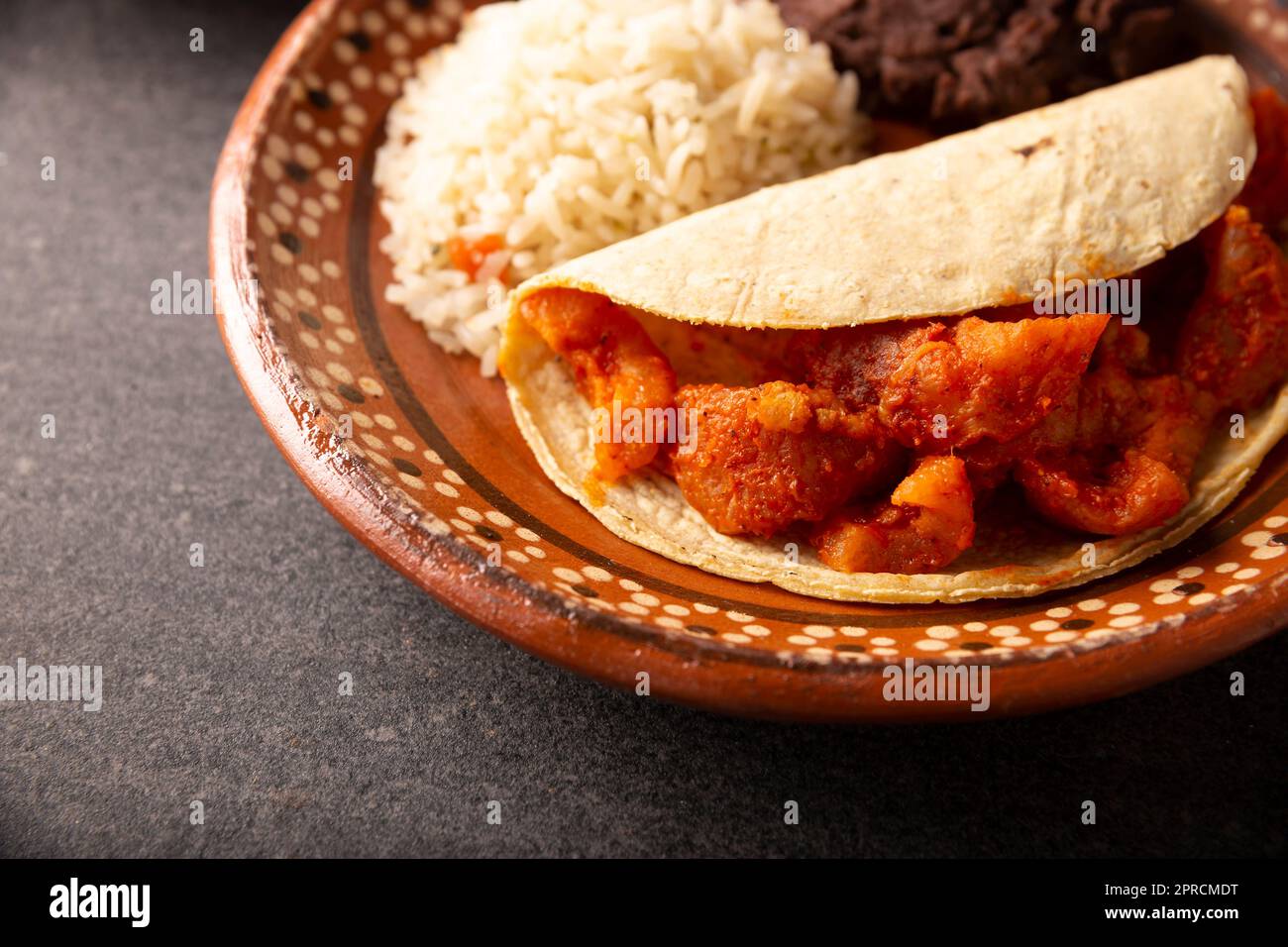 Pork rinds in red sauce Taco accompanied by rice and refried beans. Traditional homemade dish very popular in Mexico, this dish is part of the popular Stock Photo