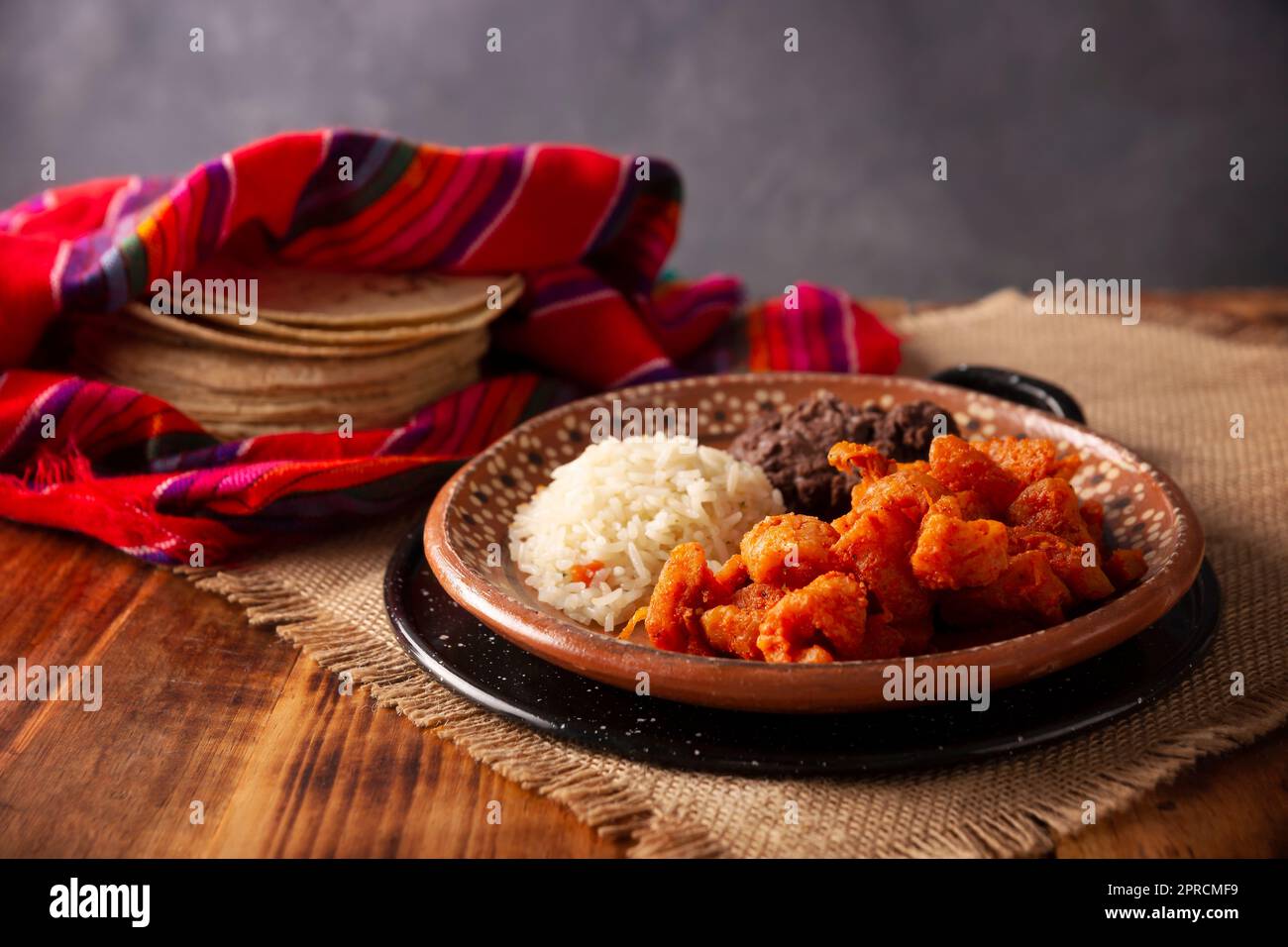 Pork rinds stewed in red sauce accompanied by rice and refried beans. Traditional homemade dish very popular in Mexico, this dish is part of the popul Stock Photo