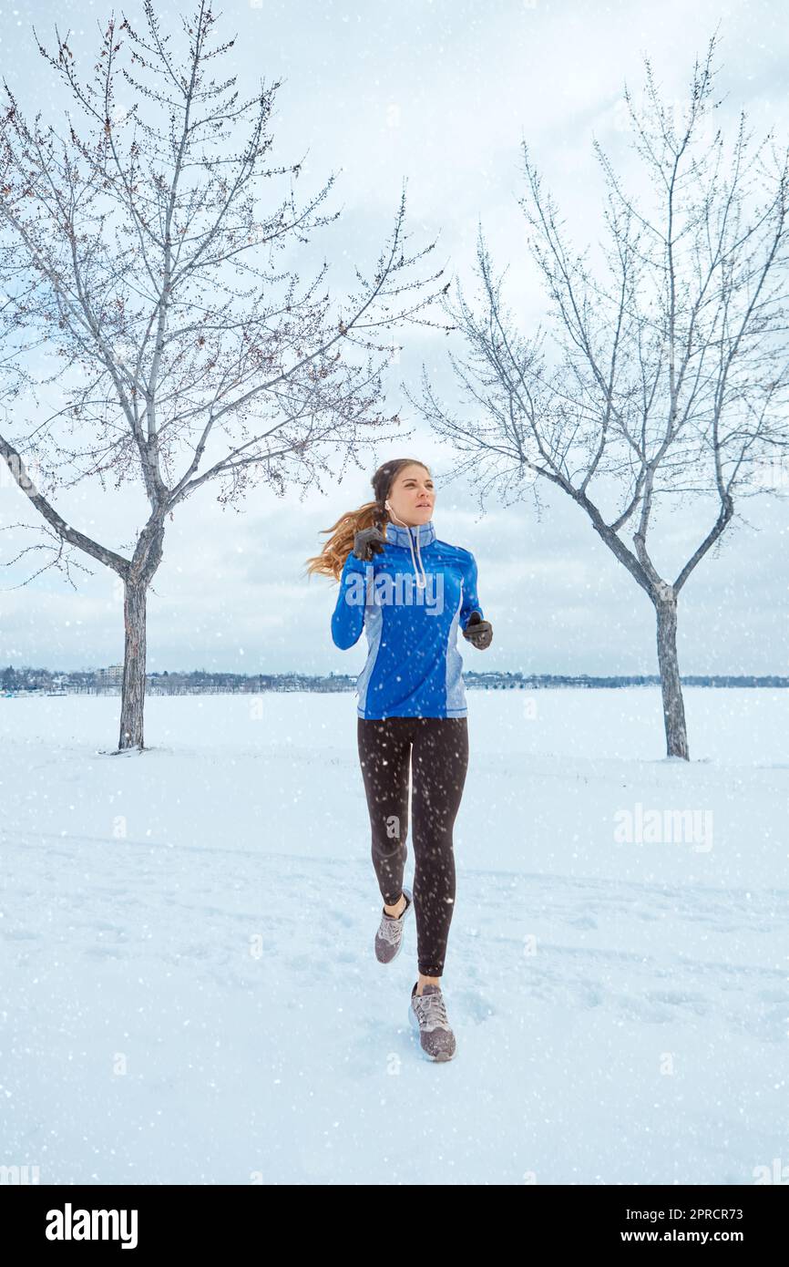 Summer bodies are made in winter. a woman wearing warm clothing while out  for a run through the snow Stock Photo - Alamy