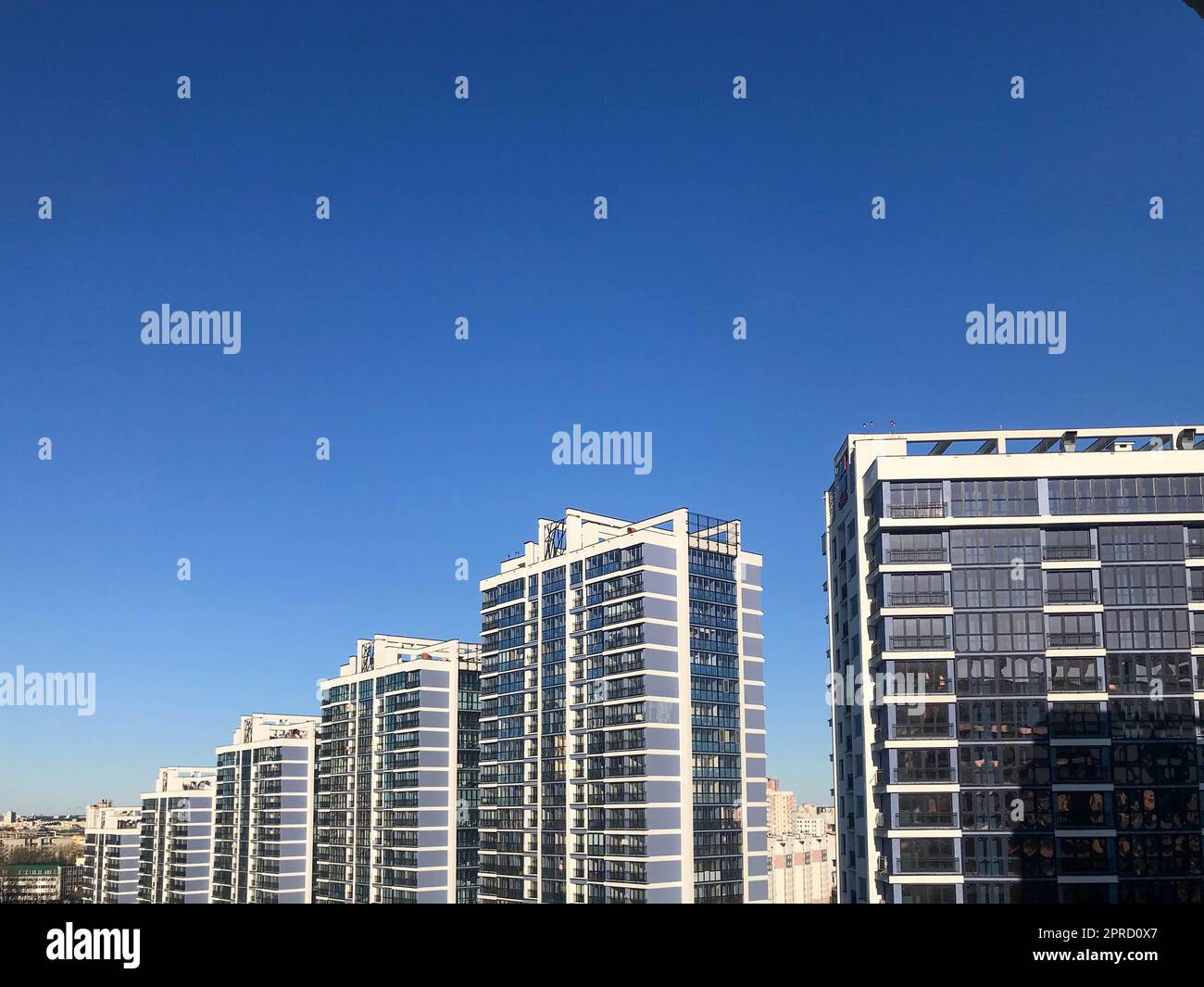the tops of tall blue glass houses against the pale blue sky. a ...
