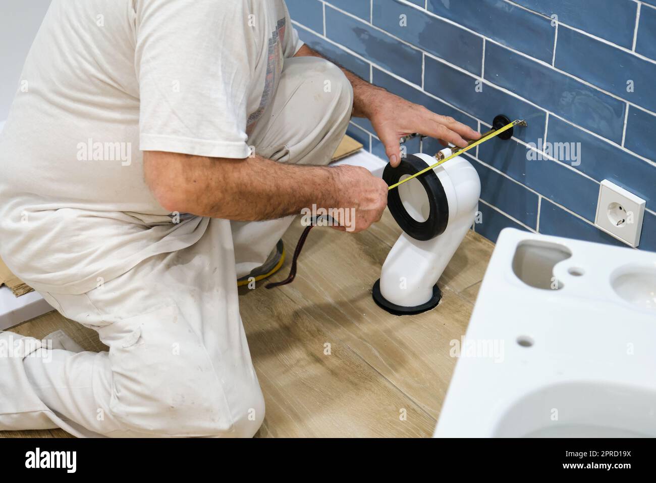 Unrecognizable senior plumber installer installing toilet drain flange