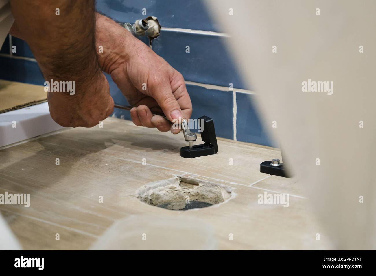 Unrecognizable senior plumber installer installing toilet drain flange