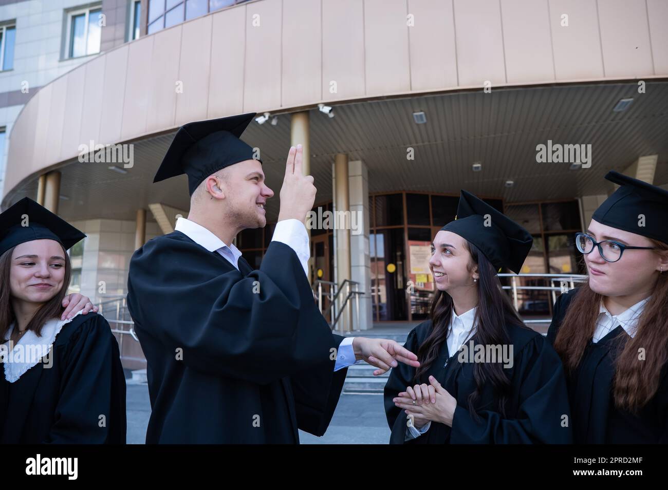 Happy students in graduate gown communicate in sign language Stock ...