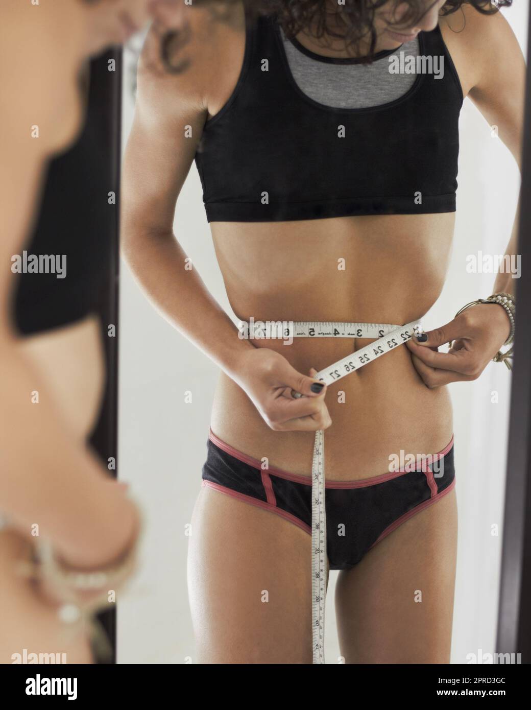 Anorexia, measuring tape and stomach of woman in mirror for weight loss, eating disorder and body image. Depression, mental health and sad with female Stock Photo