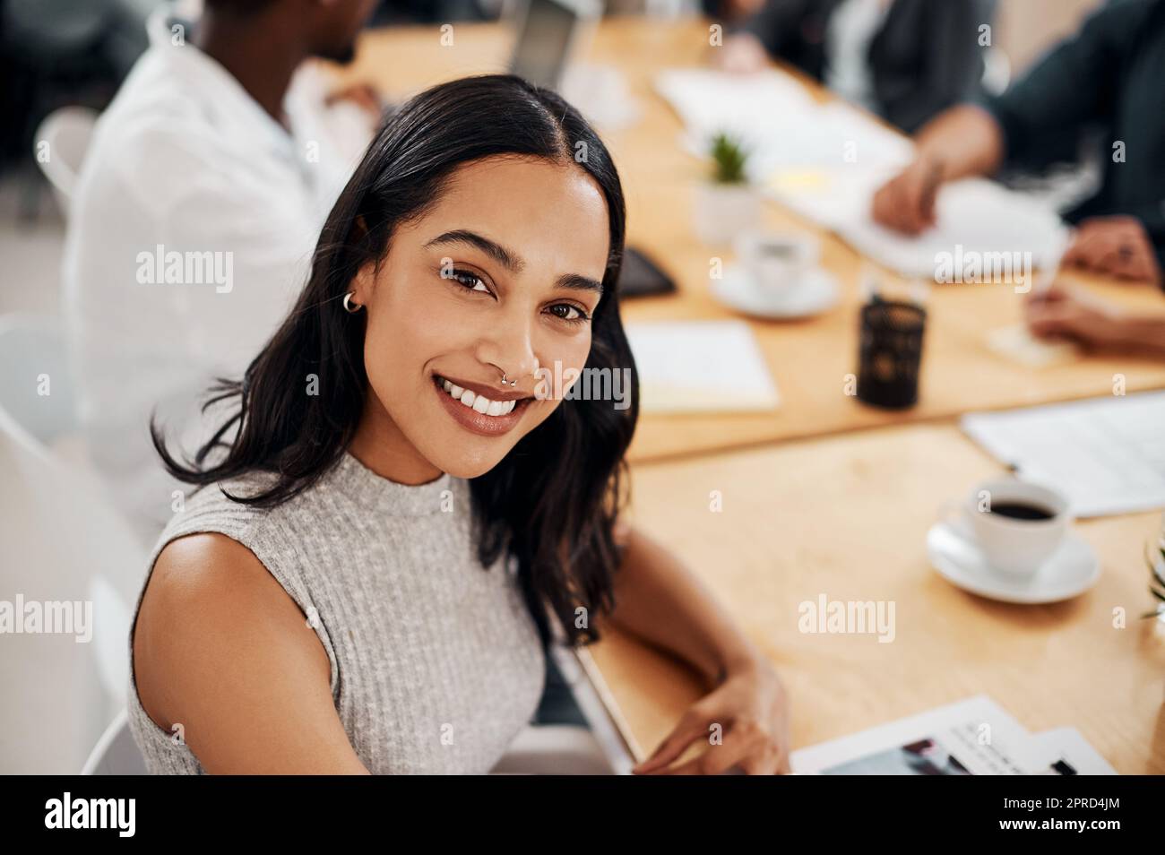 Ive reached a great sense of fulfilment in my career. Portrait of a young businesswoman sitting in an office with her colleagues in the background. Stock Photo