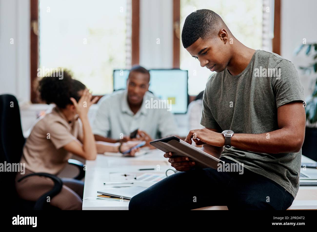 The perfect tool for a modern manager. a young businessman using a digital tablet during a meeting in a modern office. Stock Photo