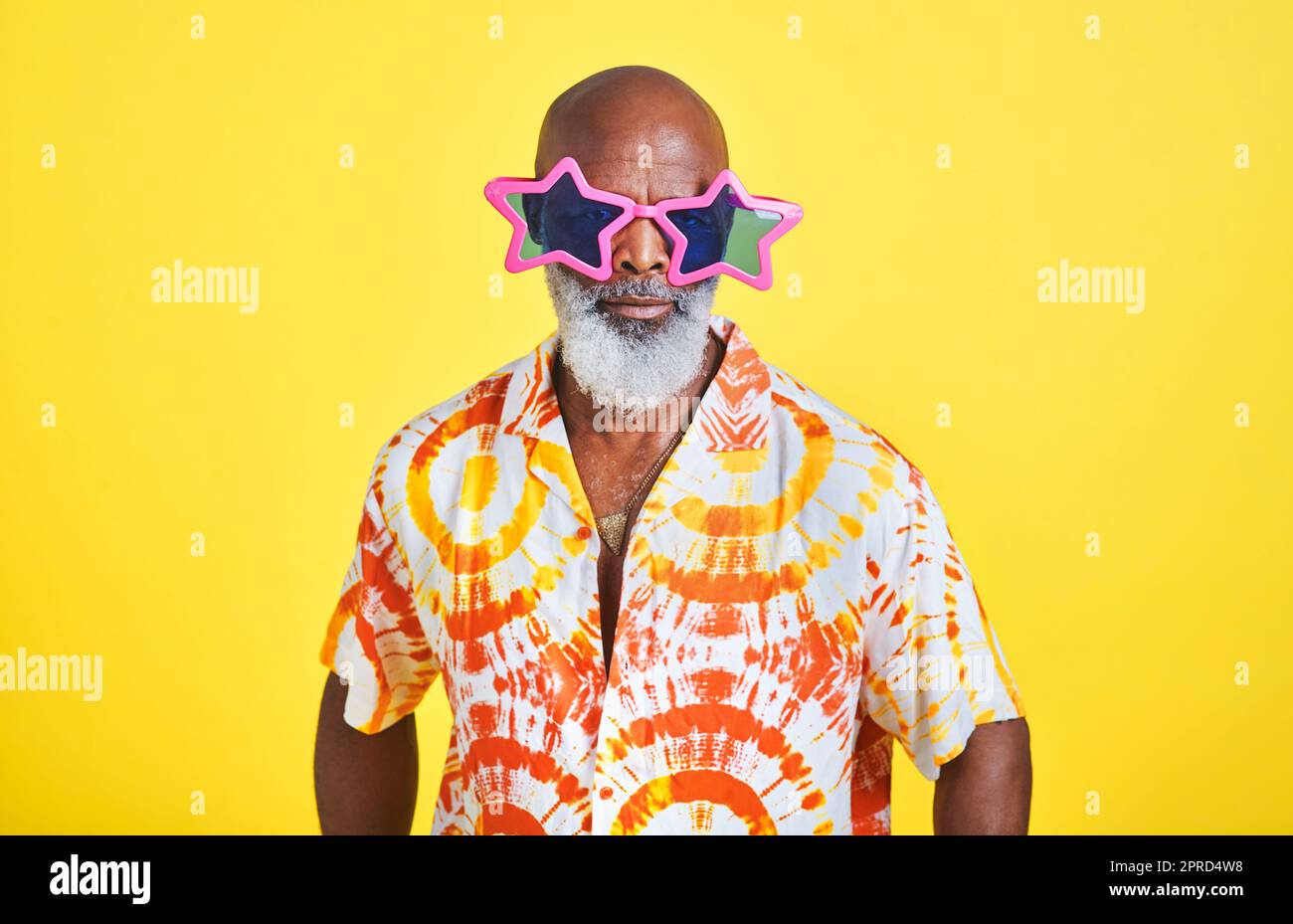 Im always the star attraction. Portrait of a funky and stylish senior man wearing sunglasses posing in studio against a yellow background. Stock Photo