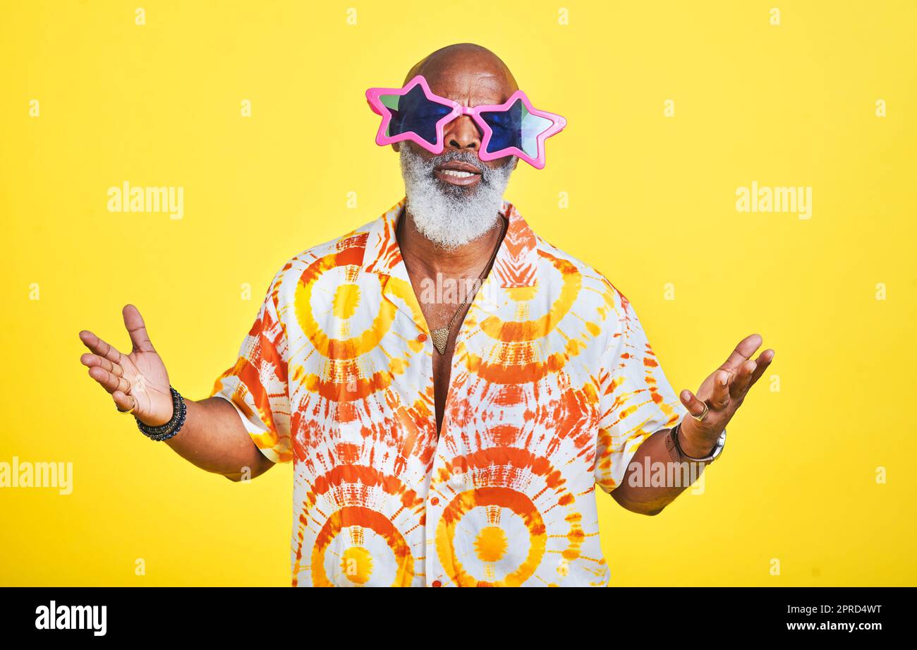 Blame it on the swag man. Portrait of a funky and stylish senior man wearing sunglasses posing in studio against a yellow background. Stock Photo