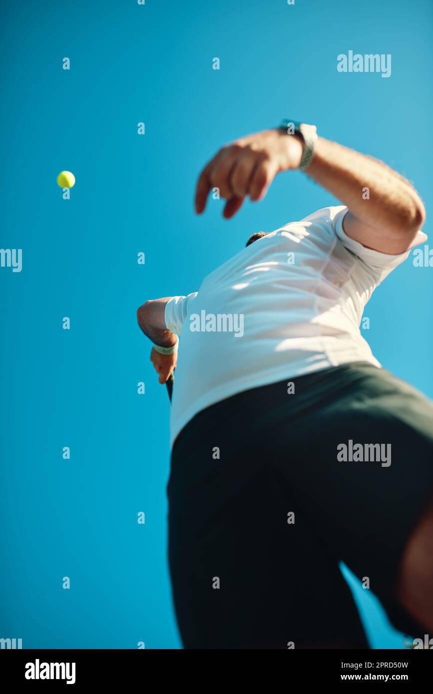 Set your goals high and dont stop till you get there. Low angle shot of a sporty young man playing tennis. Stock Photo