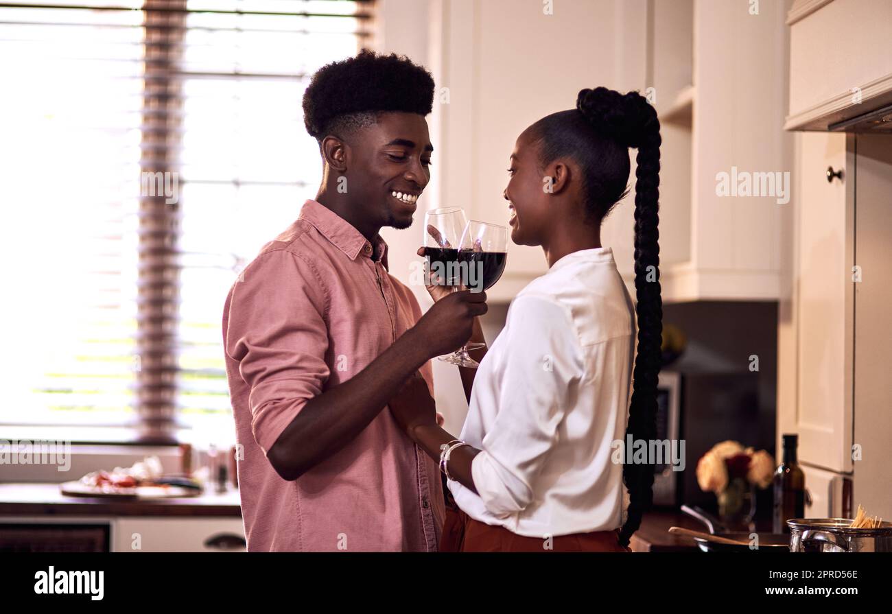 Their romance is such a cute thing. an affectionate young couple drinking wine together in their kitchen at home. Stock Photo