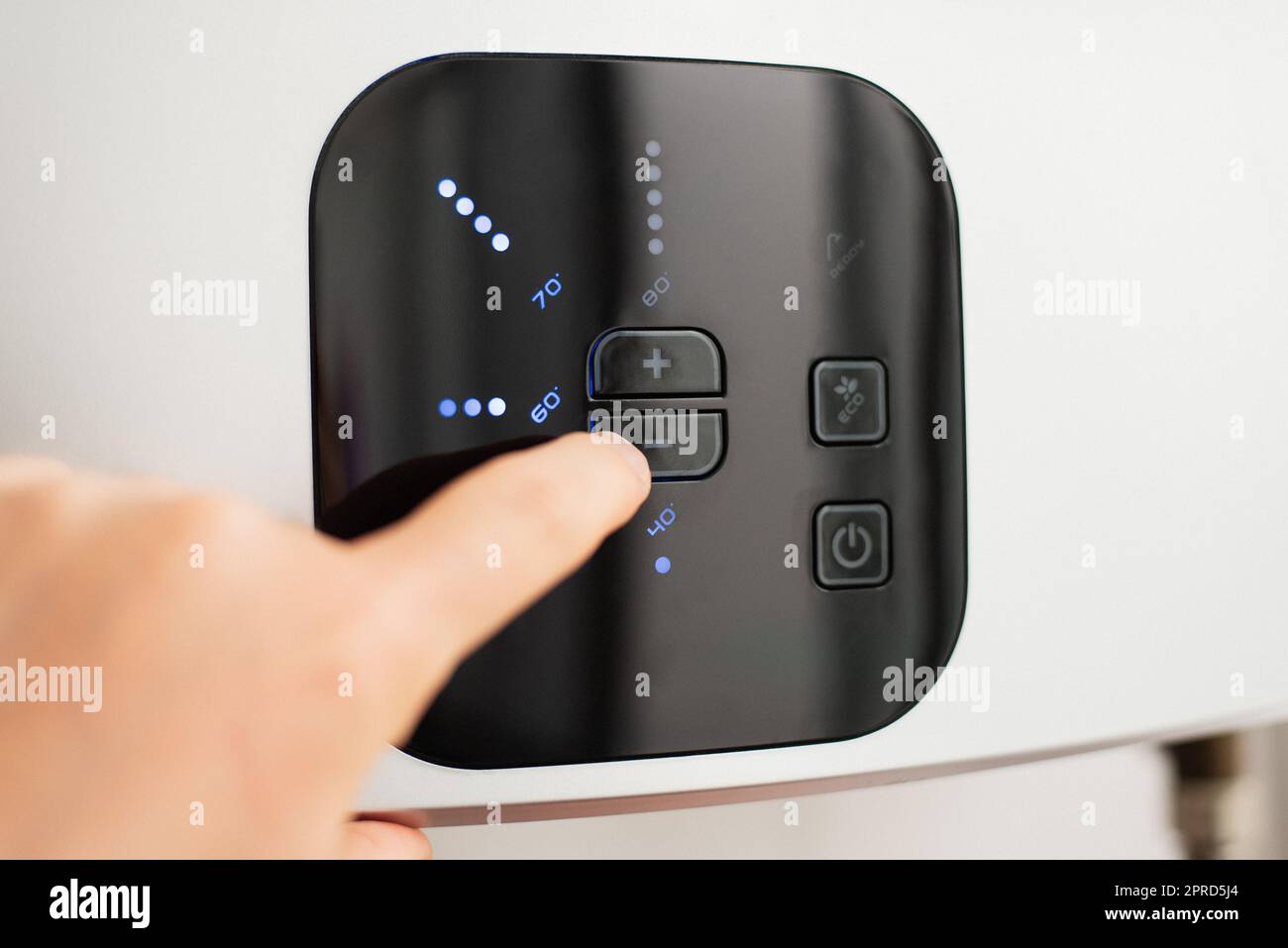 Hand lowering the temperature of hot water in electric water heater to