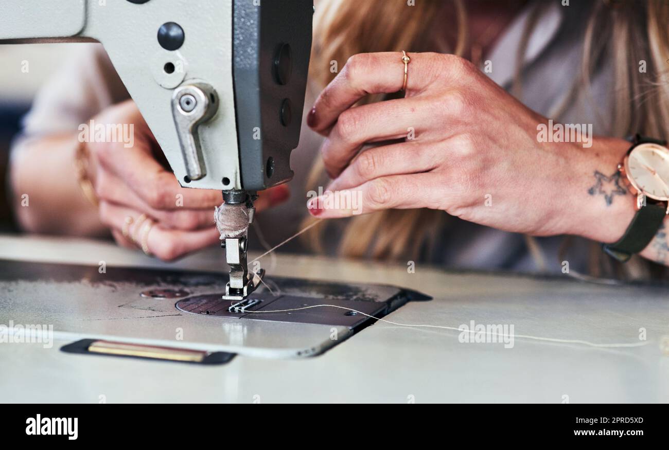 My sewing machine is my best friend. a young fashion designer using a sewing machine in her workshop. Stock Photo