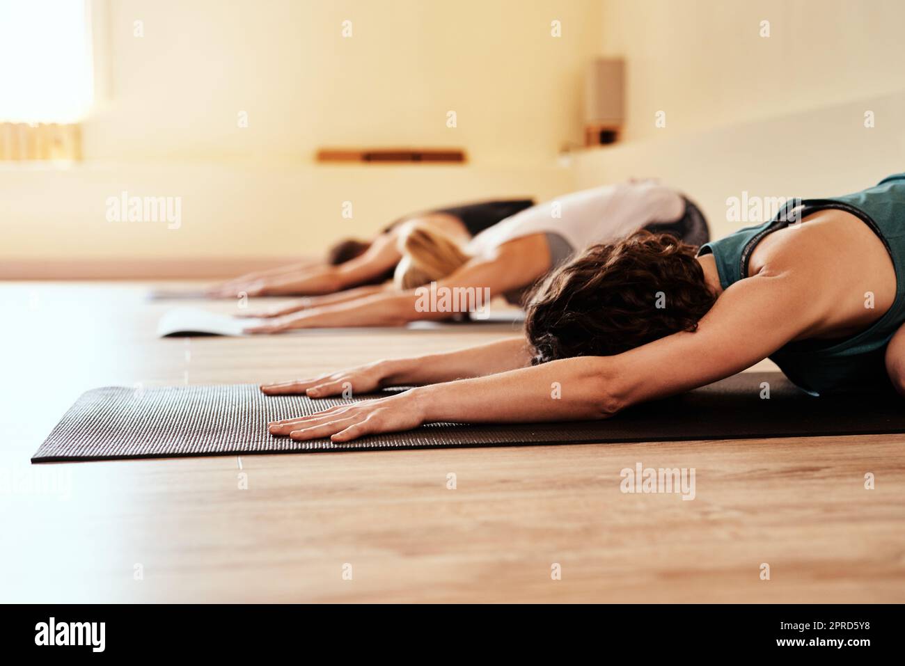 Your body is your best friend. a group of young men and women practicing the childs pose during a yoga session. Stock Photo